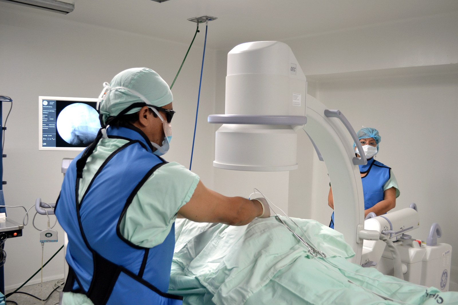 Especialista realizando un bloqueo nervioso guiado por fluoroscopia en sala de procedimientos.